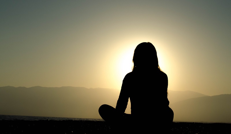 Woman in repose facing sunset